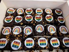 Box of brownies with Pride-themed decorations including rainbows, love messages and hearts onto an edible image.