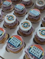 Cupcakes with Pride-themed decorations on a white surface