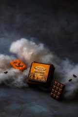 Chocolate brownie with Halloween-themed packaging on a dark surface with smoke effect