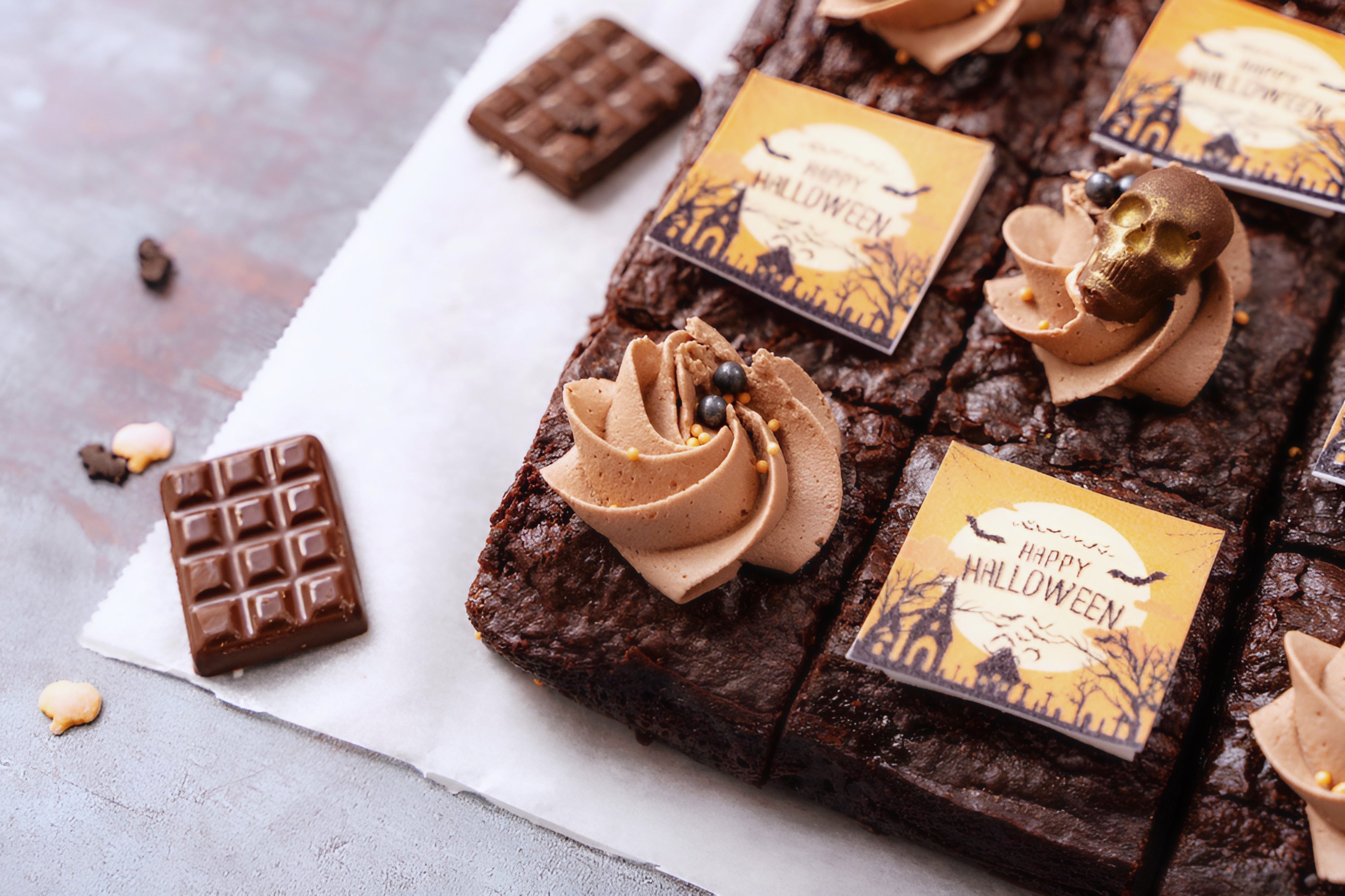 Brownies with Halloween-themed decorations and labels on a gray surface