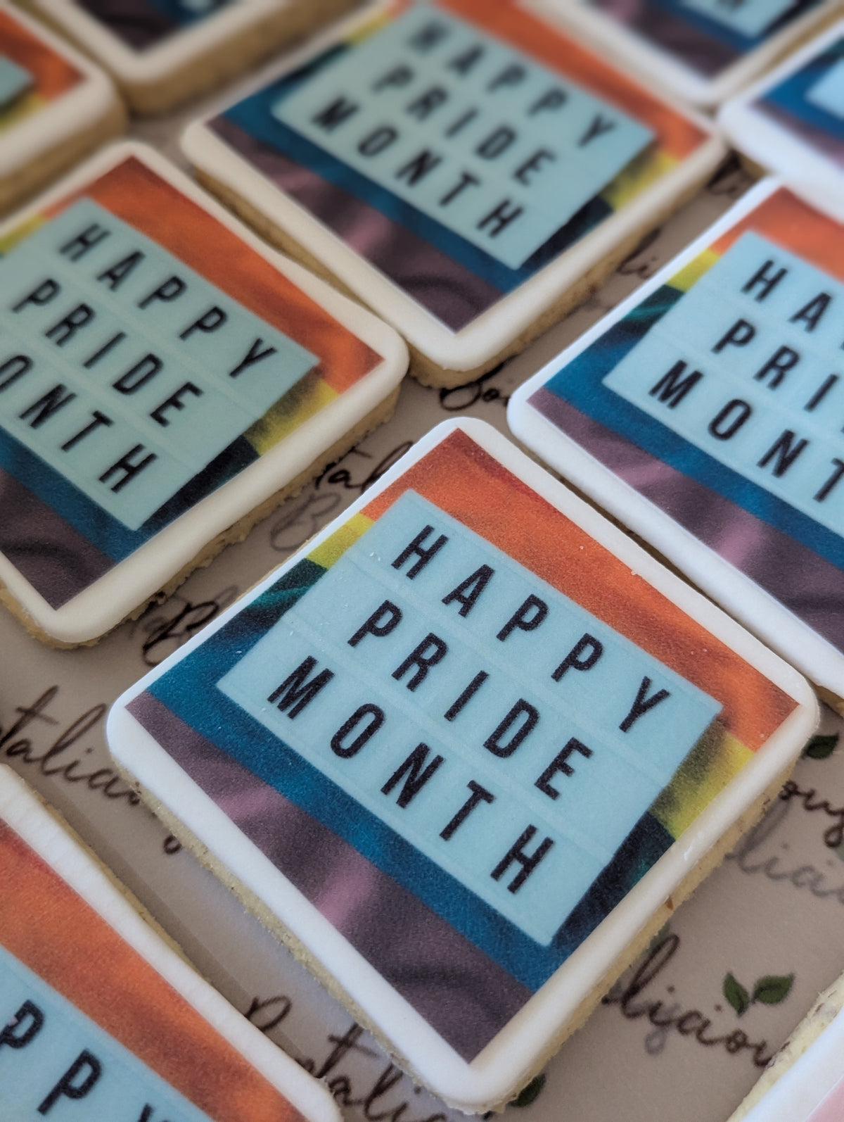 Cookies with 'Happy Pride Month' text on a surface with visible text underneath.